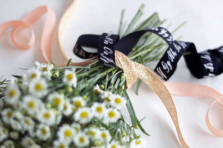 Gently thread the calligraphy ribbon under the first two. Pull one end through so that it hangs about the same length as the stems, leaving the other end long. Secure with a small pin pushed towards the center of the bouquet.